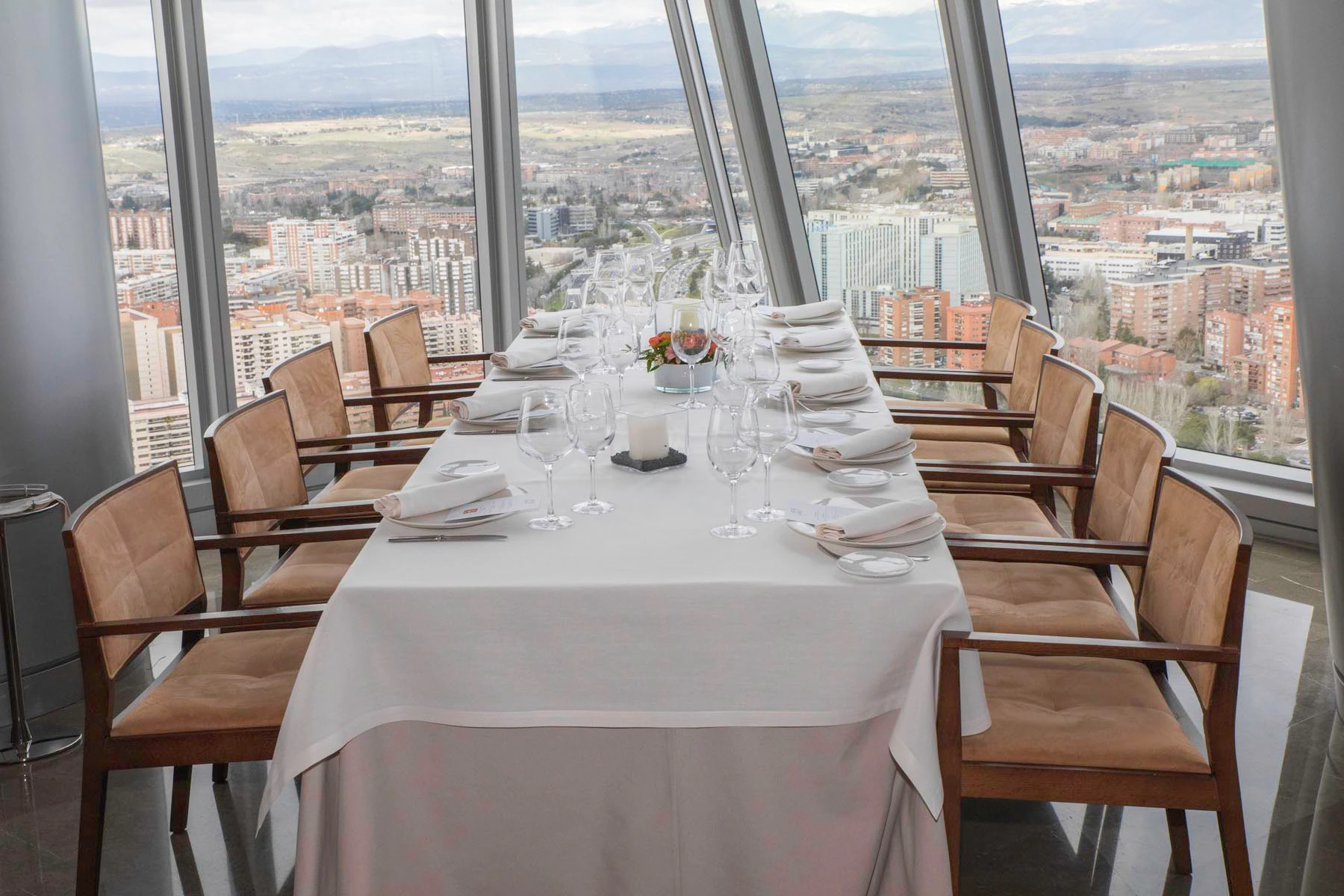 Mesa preparada para cena de gala corporativa en rascacielos de Madrid con vistas panorámicas, ideal para presentaciones de producto, reuniones directivas y celebraciones de empresa