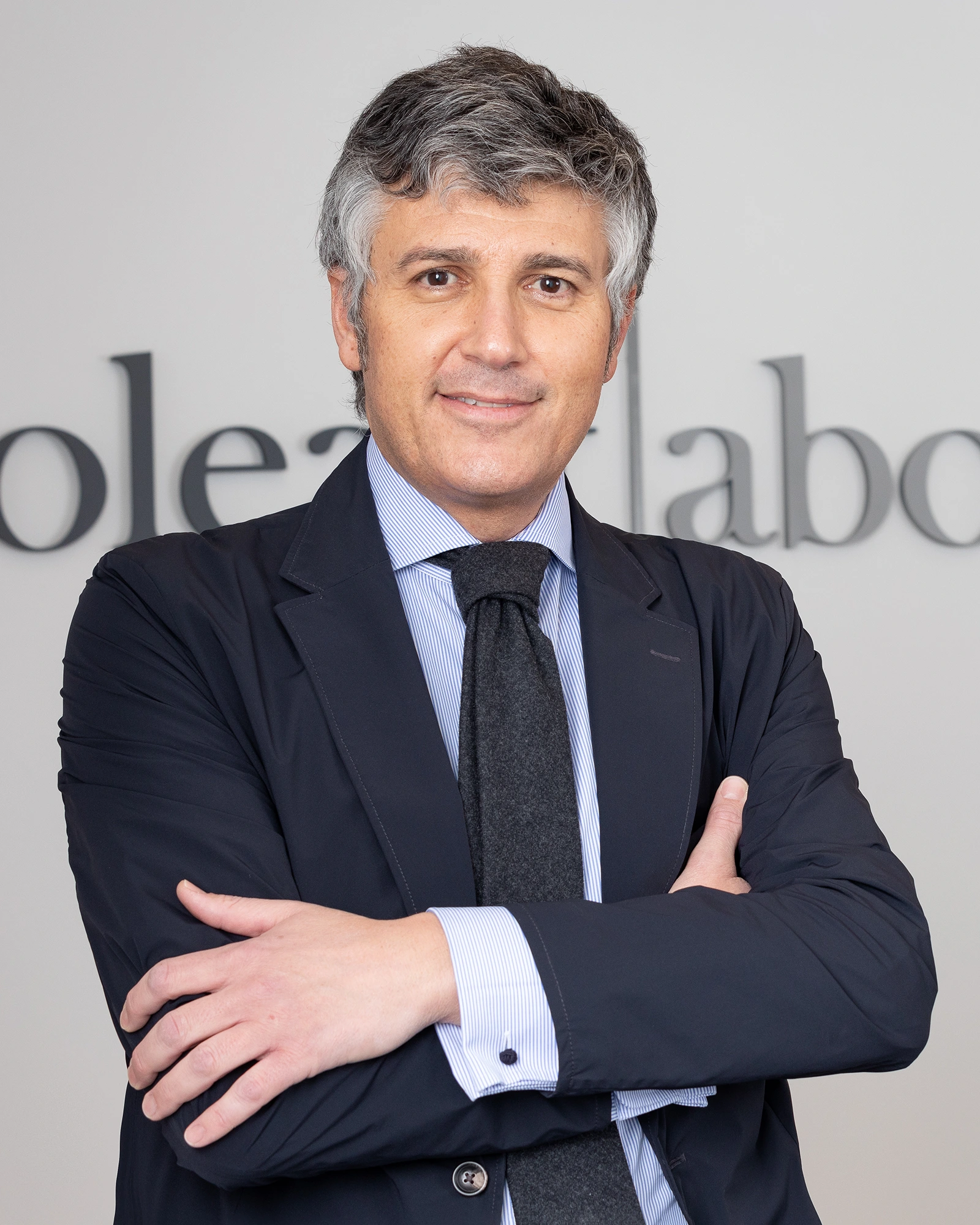 Retrato corporativo de abogado con brazos cruzados en despacho profesional