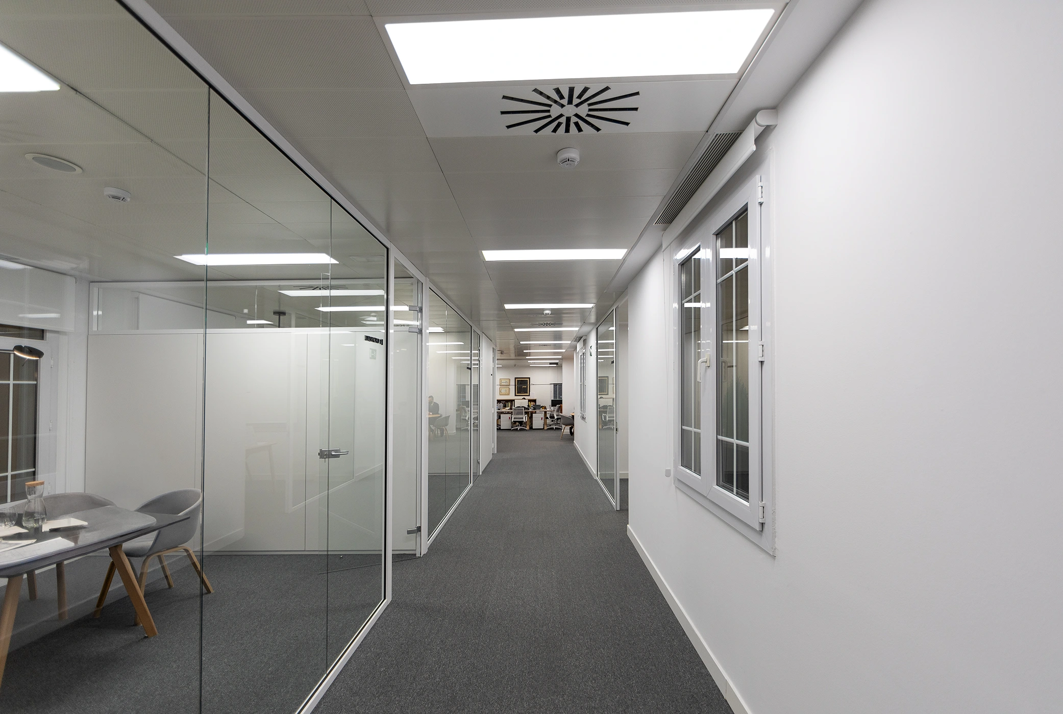 Fotografía de pasillo de oficinas modernas con mamparas de cristal
