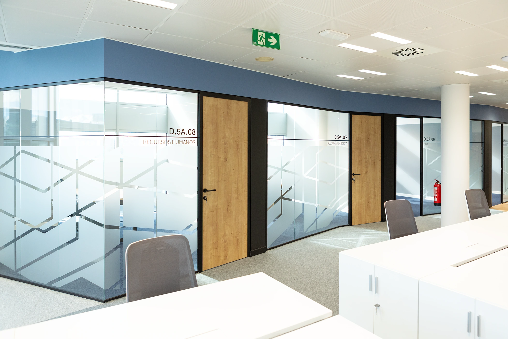Fotografía de interiores de oficina corporativa con mamparas de cristal y despachos