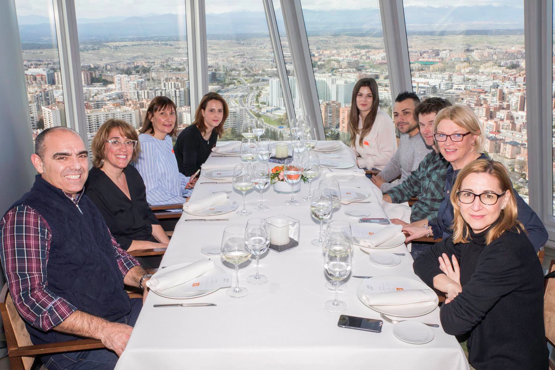Equipo de empresa durante comida corporativa en restaurante con vistas panorámicas desde rascacielos de Madrid